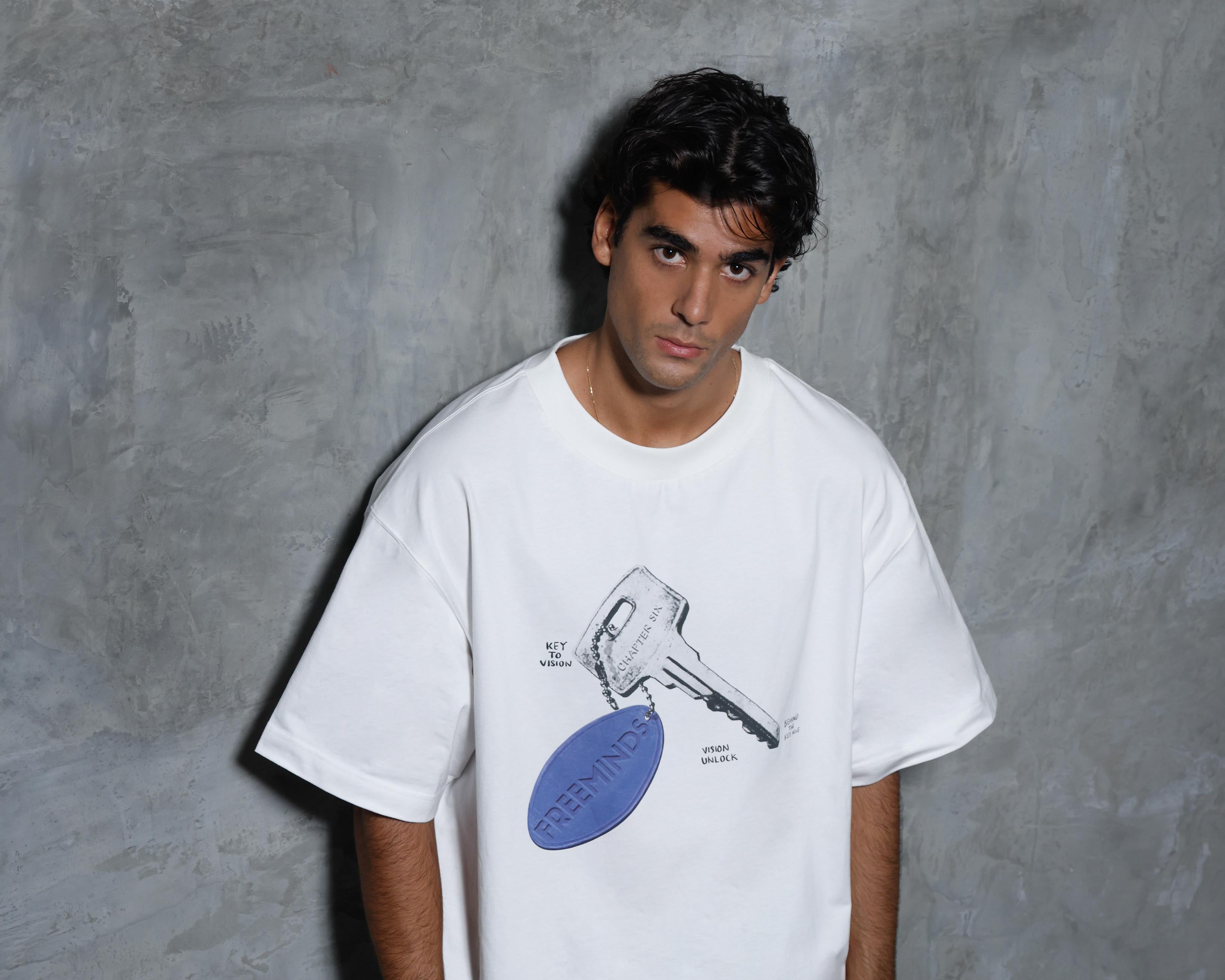 Person wearing a white t-shirt with a graphic design against a gray background